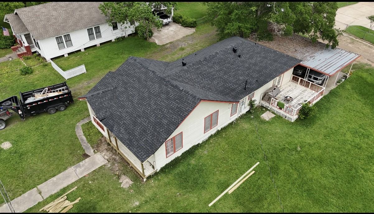 White farmhouse with completed dark shingle roof